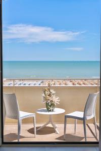 uma mesa e cadeiras numa varanda com praia em Hotel Orchidea em Cervia