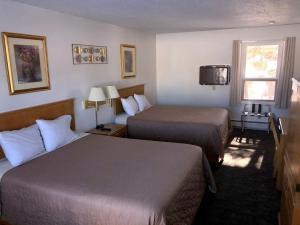 a hotel room with two beds and a television at Budget Host Inn in Ironwood