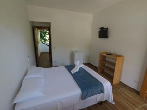 a bedroom with a large white bed and a dresser at Pousada Recanto das Margaridas in Boicucanga +60 photos