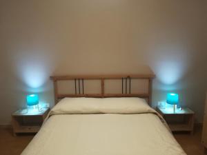 a bedroom with a bed with two blue lamps on tables at Kite Francy's house in Marsala