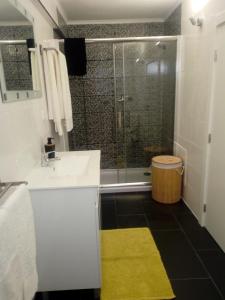 a bathroom with a sink and a shower with a yellow rug at Casa do soito in Mangualde