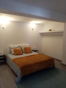 a bedroom with a large bed with two orange pillows at Casa do soito in Mangualde