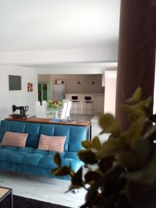 a living room with a blue couch and a kitchen at Casa do soito in Mangualde