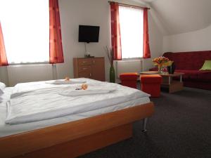 um quarto com uma cama e um sofá vermelho em Penzion Oregano Třeboň em Třeboň