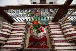 a stack of books with a vase of flowers on top at Riad Atlas Mejbar in Marrakesh