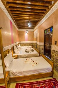 a bedroom with two beds with white sheets and a window at Riad Atlas Mejbar in Marrakesh