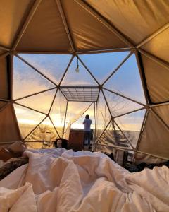 Ein Mann steht in einem Zelt mit einem Bett in der Unterkunft Glamping La Montaña Sagrada in Medellín