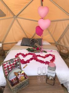 a bed with balloons and two baskets of food and drinks at Glamping La Montaña Sagrada in Medellín