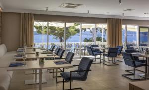 een restaurant met tafels en stoelen en uitzicht op de oceaan bij Aminess Bellevue Village in Orebić