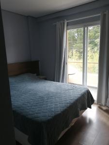 Schlafzimmer mit einem Bett und einer Glasschiebetür in der Unterkunft CAPIVARI conforto in Campos do Jordão