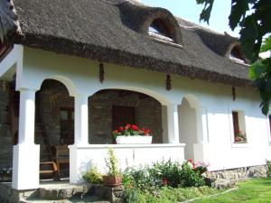 a cottage with a thatch roof and a flower pot at Csátó Vendégház in Tihany