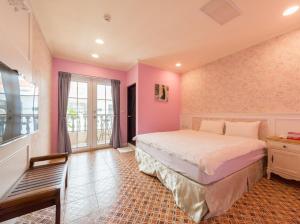 een slaapkamer met een groot bed in een kamer met roze muren bij Pretty Nanwan B&B in Nanwan