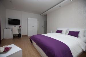 1 dormitorio con 1 cama grande con almohadas moradas en Rooms Ino, en Kaštela