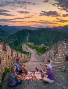 Encounter Garden Great Wall Holiday Guesthouse في بكين: مجموعة من الناس يجلسون حول نزهة على الجدار العظيم