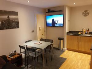 een woonkamer met een tafel en een tv aan de muur bij Birmingham Garnet, 3 bedroom Apartment in Birmingham