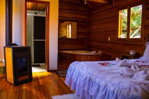 a bedroom with a bed and a bath room with a tub at Pousada Cascata Véu de Noiva in Urubici