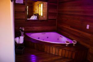 a bath tub in a wooden bathroom with a woman in a mirror at Pousada Cascata Véu de Noiva in Urubici +76 photos