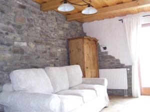 a living room with a white couch and a stone wall at Csátó Vendégház in Tihany