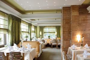 a restaurant with white tables and chairs and windows at Ferienhotel Ödenhof in Baiersbronn