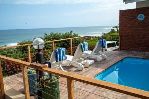 a deck with chairs and a swimming pool and the ocean at Sea View townhouse in Zinkwazi Beach in Zinkwazi Beach