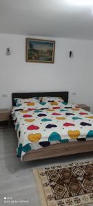 ein Bett mit farbenfroher Bettdecke in einem Schlafzimmer in der Unterkunft Casa M in Câmpulung Moldovenesc