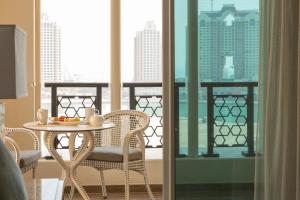 a table and chairs on a balcony with a view at Retaj Baywalk Residence in Doha