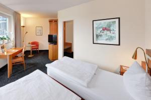 a hotel room with two beds and a desk at Ringhotel Parkhotel Witten in Witten