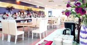 um restaurante com cadeiras e mesas brancas e flores roxas em Phuong Hoang Hotel em Thanh Hóa