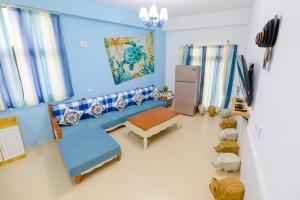 Una sala de estar con un sofá azul y una mesa. en Gold Coast B&B, en Huxi