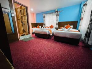two beds in a hotel room with red carpet at Rosemary Homes Pokhara in Pokhara