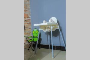 a table with a green chair next to a wall at PNG Guest house Kitende in Kampala