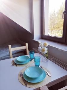 a table with plates and glasses and a window at Prokocim Apartments in Kraków