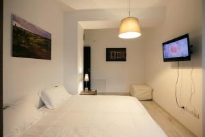 a bedroom with a large white bed and a flat screen tv at Urban Homy Gorizia in Gorizia