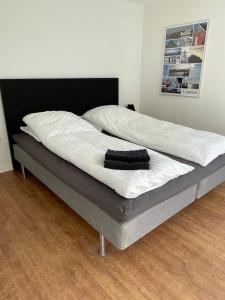 a large bed with white sheets and a black headboard at Surfers Paradise Apartments in Hvide Sande