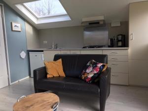 a black couch in a kitchen with a skylight at 't Hok in Hollum