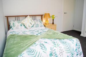 a bedroom with a bed with a green and white comforter at Botanical Guest House in Mickleham