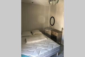 Dormitorio pequeño con cama y espejo en Grand appartement 2 minutes plage et commerces, en Saint-Cyprien
