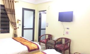 a bedroom with a bed and two chairs and a tv at SaPa Peace Valley hotel in Sa Pa