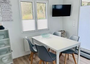 einen weißen Tisch und Stühle in einem Zimmer mit Fenstern in der Unterkunft Beach Chalet SunHus - modernes Chalet in Ostseenähe in Scharbeutz