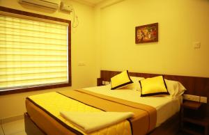 1 dormitorio con 2 camas y ventana en Sree Janardhana Residency, en Kollam
