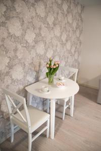 une table blanche avec deux chaises et un vase de fleurs dans l'établissement Mia Kiviõli Apartment, à Kiviõli