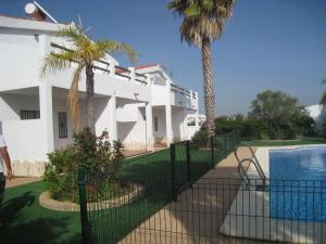 a white house with a swimming pool and palm trees at Apartamentos Los Olivos in Conil de la Frontera