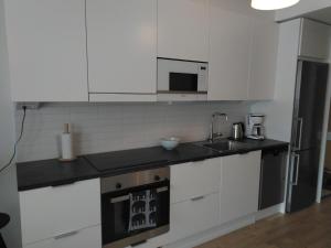a kitchen with white cabinets and a sink and a stove at Lutakko Apartment 2 with free car parking in Jyväskylä