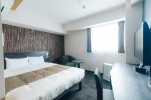 a hotel room with a bed and a tv at Hotel KAN-RAKU Fujisan Gotemba in Gotemba