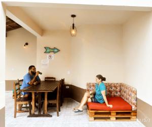 um homem e uma mulher sentados numa mesa numa sala em Lionfish Hostel em Caraguatatuba