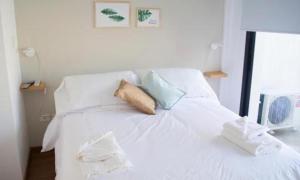 een wit bed met witte lakens en blauwe kussens bij Guemes Apart Nueva Cordoba in Cordoba
