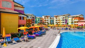 a resort with a pool and chairs and buildings at MIMOSE Lido Altanea in Caorle