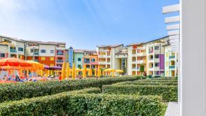 a row of apartment buildings with umbrellas and chairs at MIMOSE Lido Altanea in Caorle