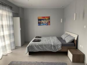 1 dormitorio con 1 cama y una pintura en la pared en Cosy studio 2 minutes walking from the beach en Anavyssos