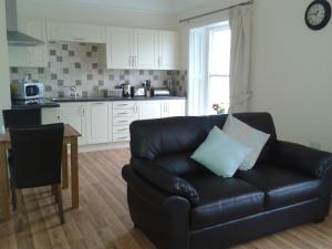 a living room with a black leather couch and a kitchen at The Bradworthy Inn in Holsworthy